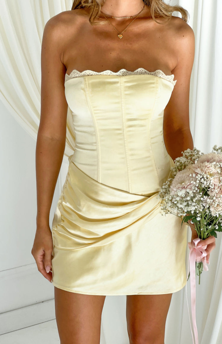 Strapless yellow satin mini dress with white lace trim, corset-style bodice, and ruched twist skirt