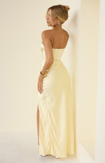 Side view of a yellow strapless satin maxi dress with ruched detailing on the hip and a high side slit
