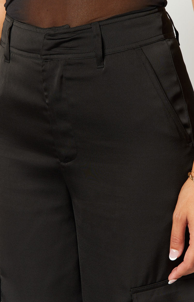 Waistband detail of black satin cargo pants with belt loops and angled front slash pockets