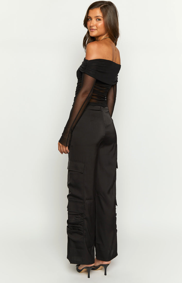 Side view of black satin cargo pants featuring large side pockets and ruched detail on the lower leg