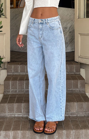 A close up image of our pair of high waisted wide leg denim jeans in a very light blue acid-wash finish. The jeans have visible front pockets and a slightly distressed hemline.