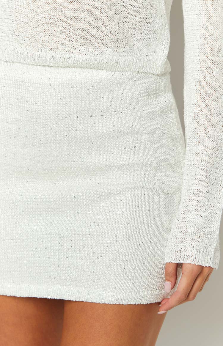 Close-up of the white sequin knit mini skirt fabric with tiny embedded silver sequins