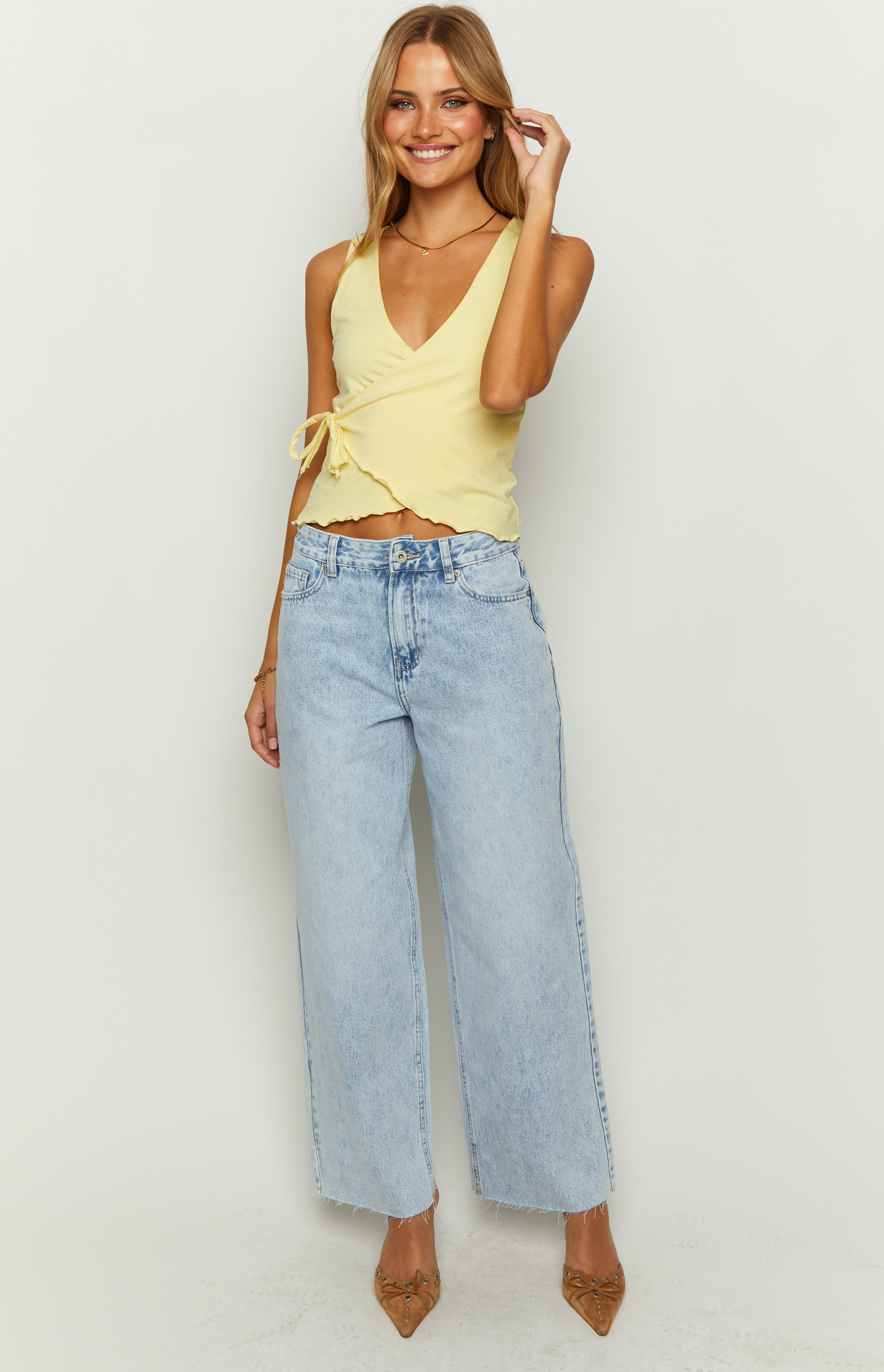 Front view of light wash denim wide leg boyfriend jeans with a high waist and raw frayed hem