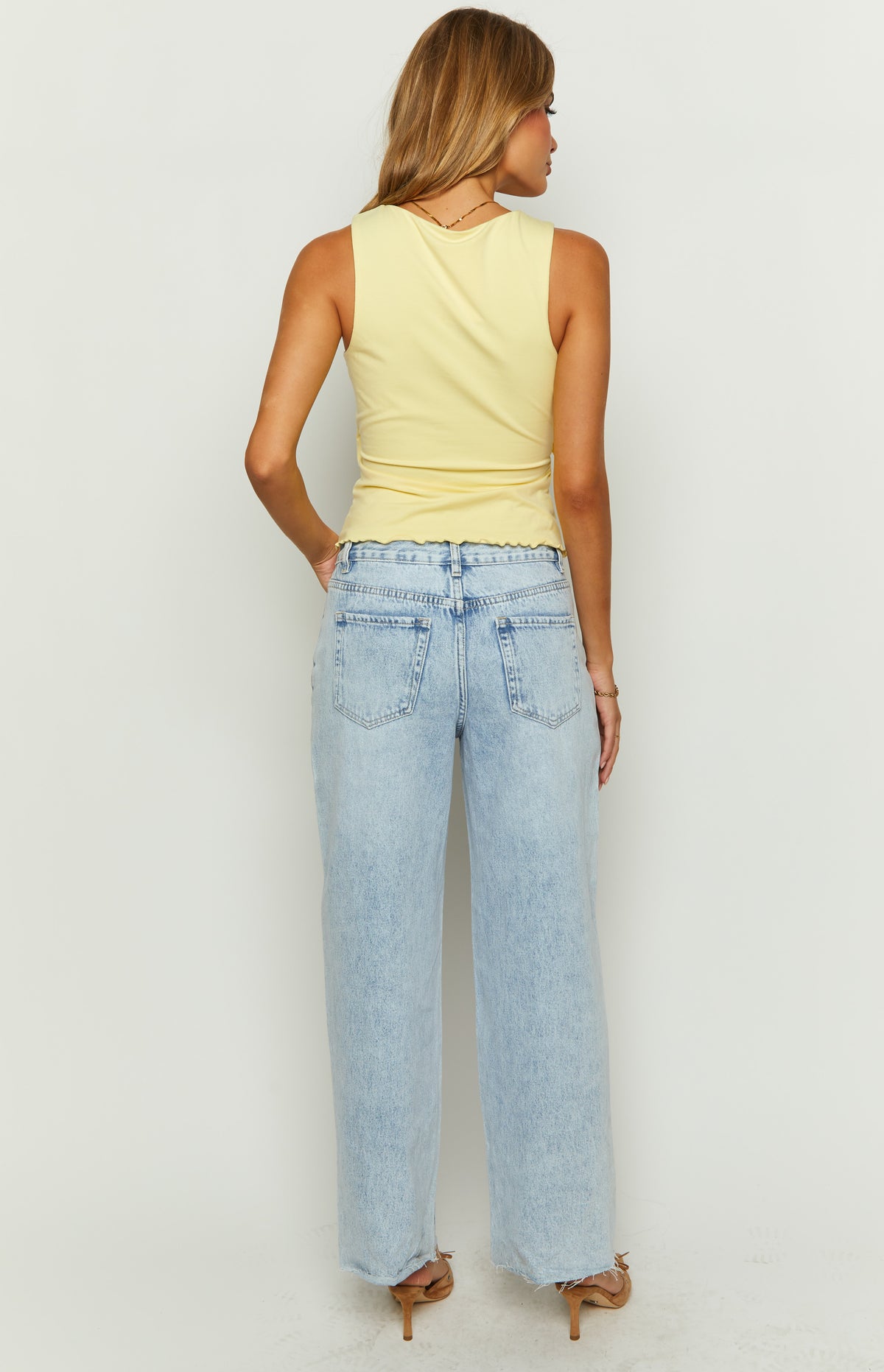 Rear view of light wash denim wide leg boyfriend jeans showing the back pockets and frayed hem
