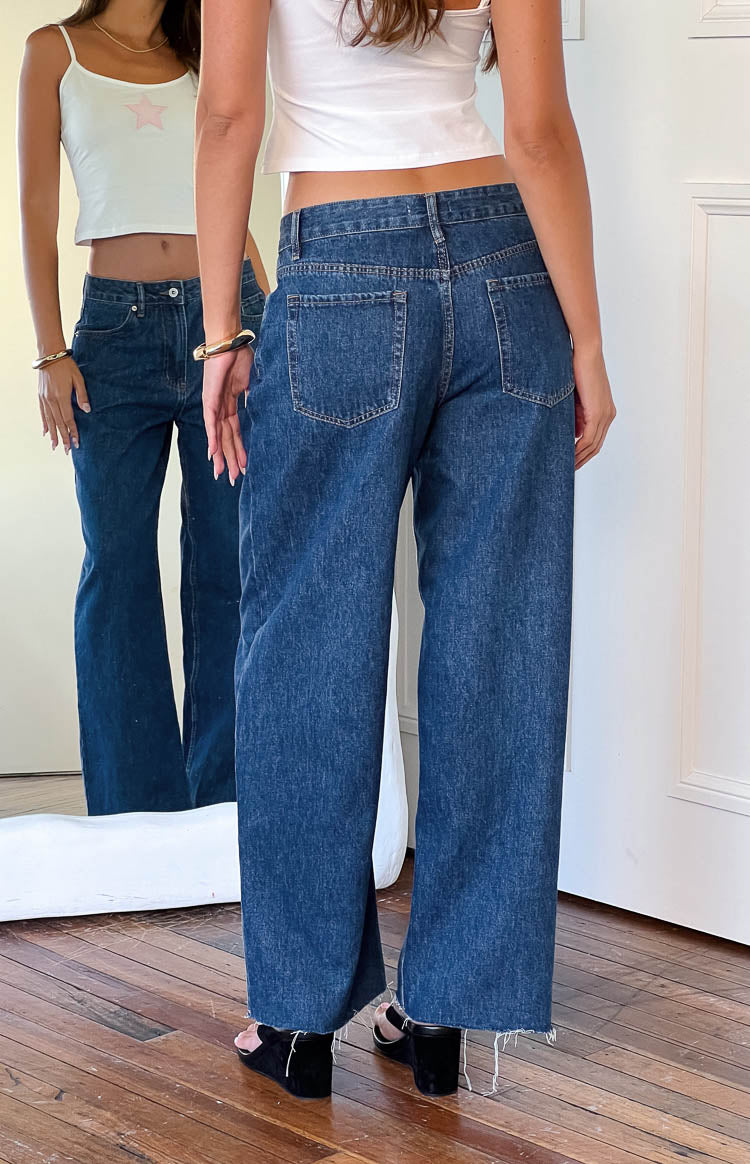 Rear view of mid wash wide leg boyfriend jeans with back pockets and a raw hem