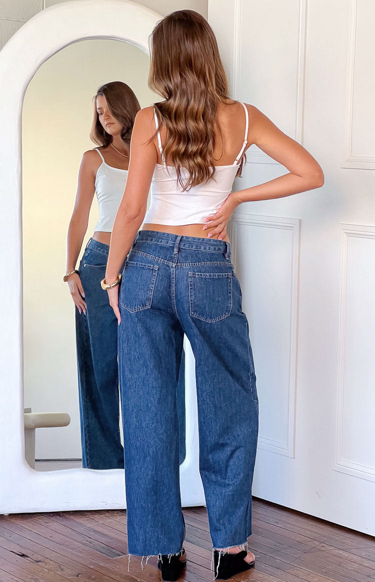 Rear view of mid wash denim wide leg jeans showing the back pockets and frayed hem