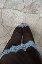 Top-down view of a brown satin top featuring wide light blue lace trim along the bottom hem