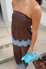 Flowy brown satin strapless top with light blue lace trim along the bottom edge