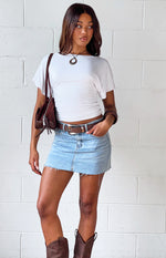 Light wash denim low rise mini skirt with a raw frayed hem and front pockets
