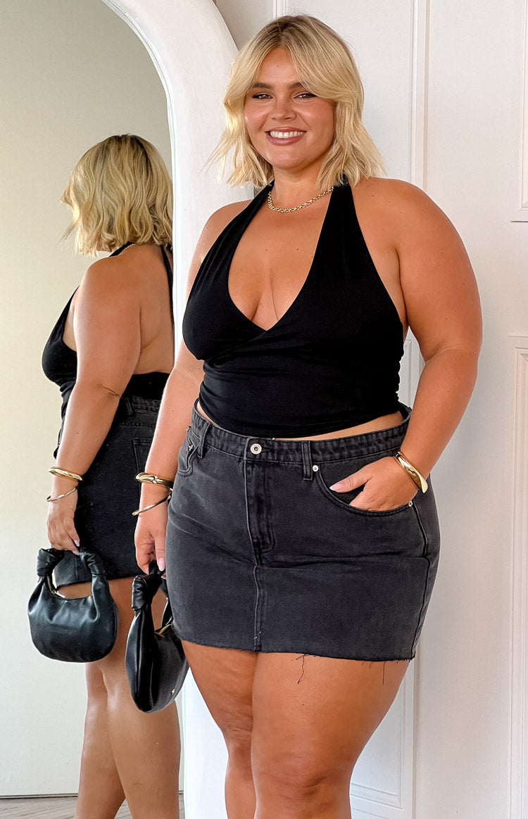 Front view of a washed black denim low-rise mini skirt with a raw frayed hem
