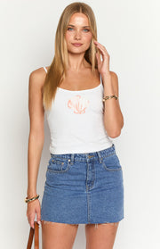 Front view of a mid wash denim low rise mini skirt with front pockets and a raw frayed hem
