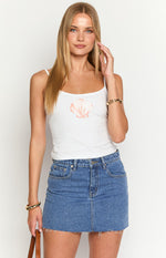 Front view of a mid wash denim low rise mini skirt with front pockets and a raw frayed hem