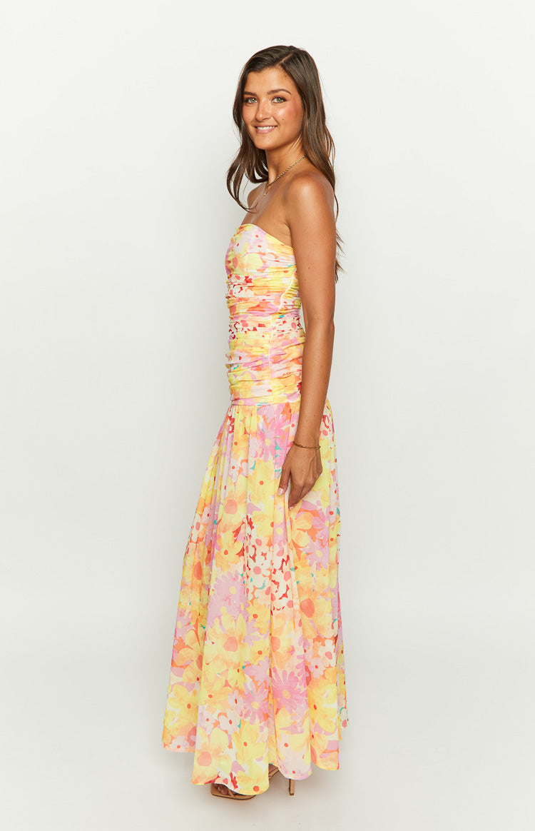 Side profile of a yellow floral strapless maxi dress showing the ruched bodice and full, flowing skirt