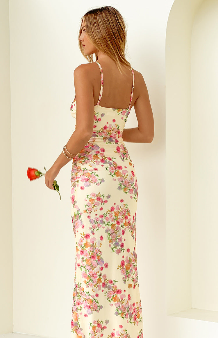 Rear-side view of a yellow floral maxi dress with thin spaghetti straps and ruched detailing on the side