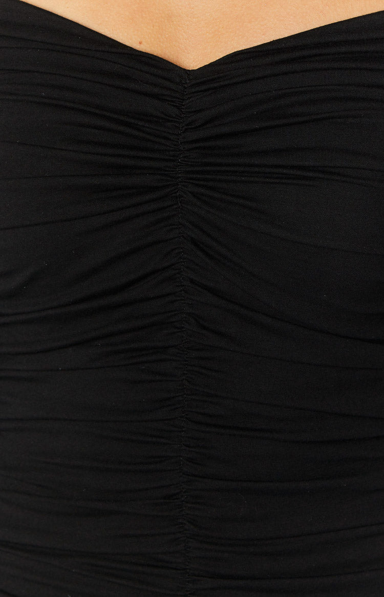 Close-up of the central ruched detail on the black mini dress, forming a sweetheart neckline