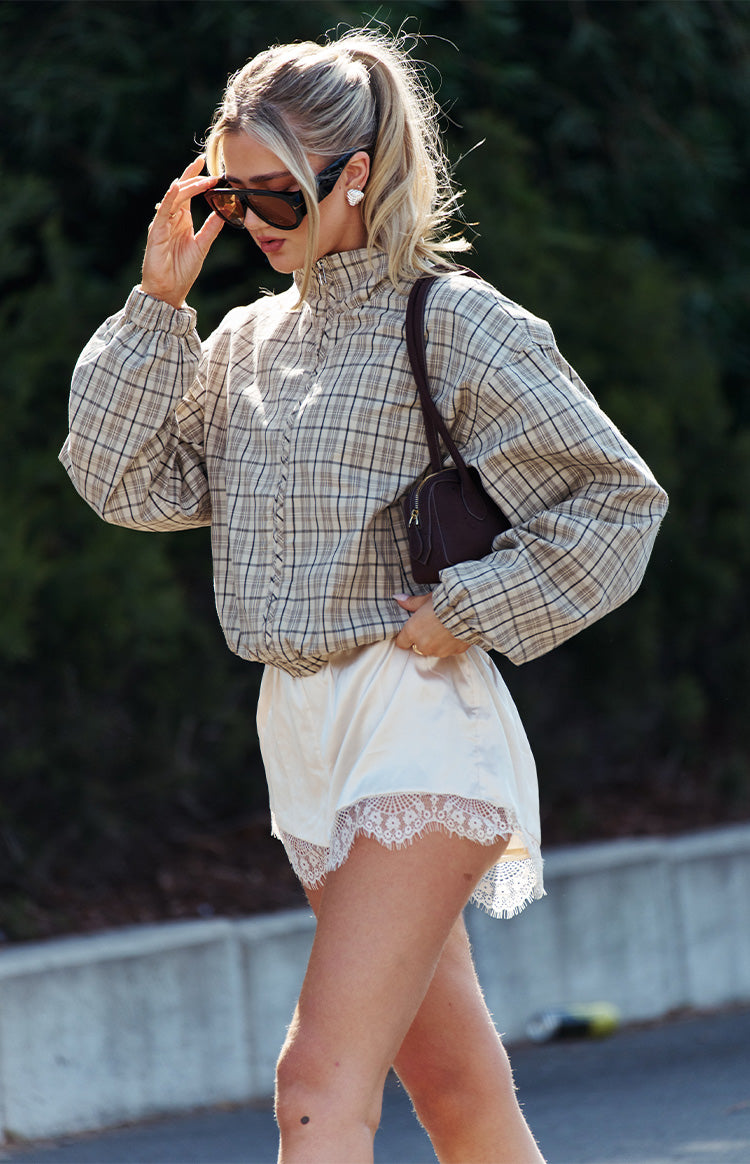 Cream satin shorts with a delicate white lace hem, showing the flowy fit from the side