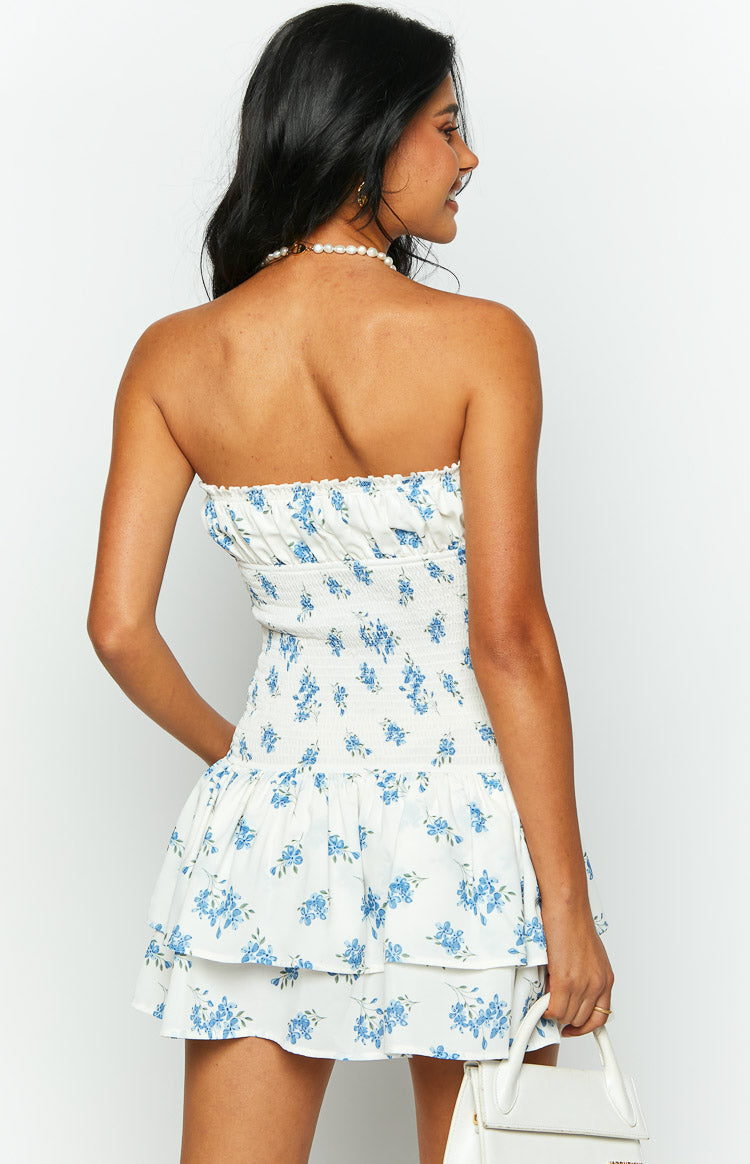Rear view showing the shirred bodice and tiered ruffle skirt of a white floral strapless mini dress