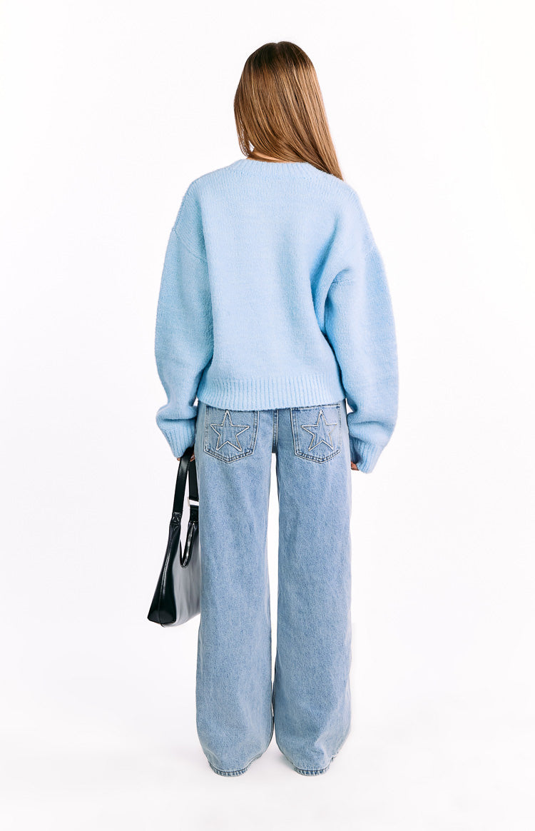 Rear view of a light blue knit cardigan with a ribbed hem and cuffs, showing its relaxed fit