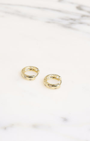 Gold hoop earrings with diamante stars and star cutouts on the inner edge, viewed from above