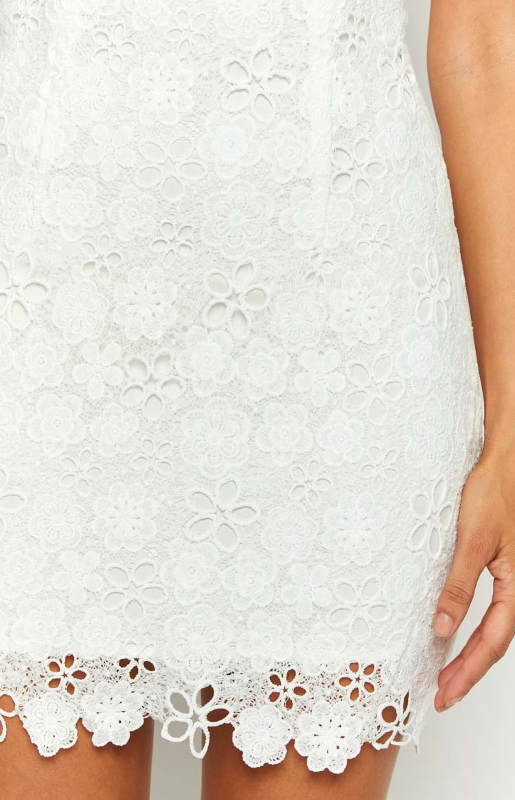 Close-up of the white floral lace fabric with a scalloped cut-out hem on a mini dress