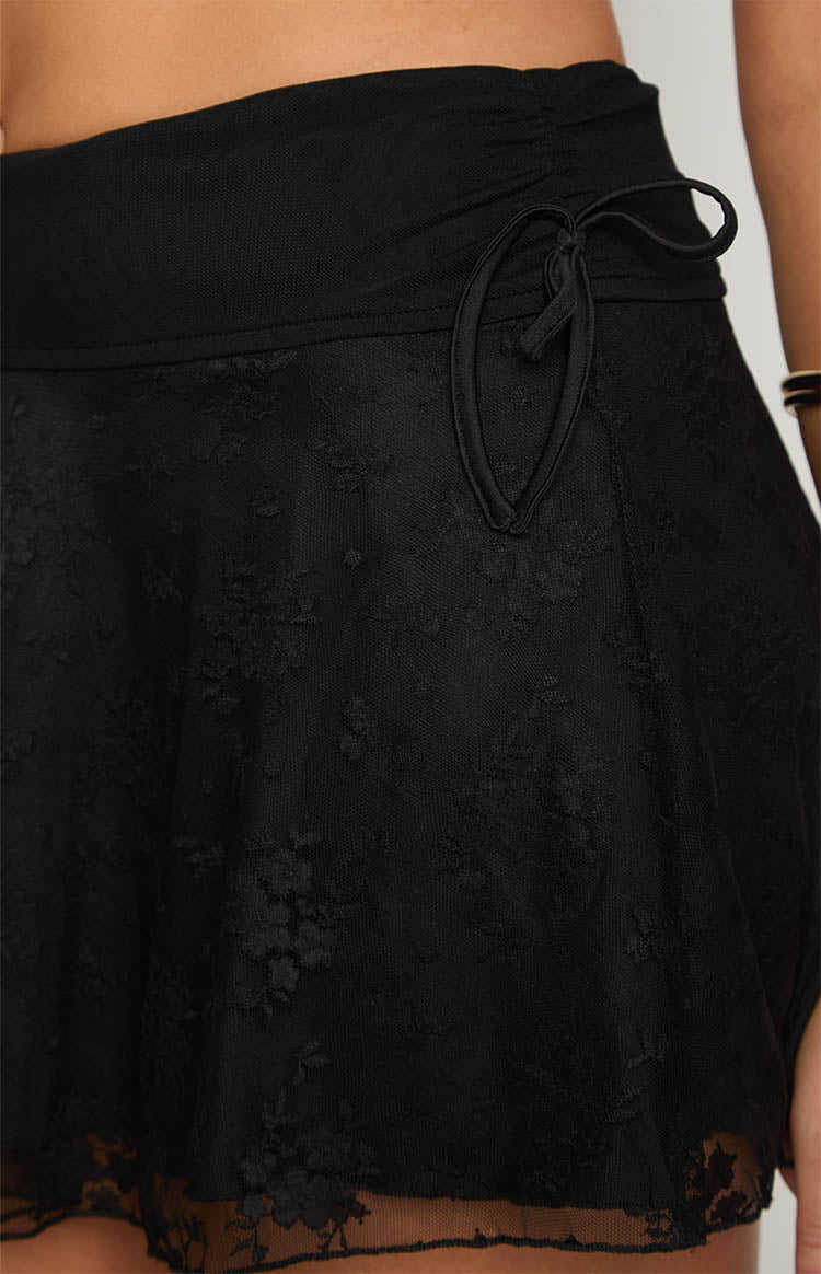 Close-up of the ruched drawstring detail on the black mini skirt's waistband and floral mesh fabric