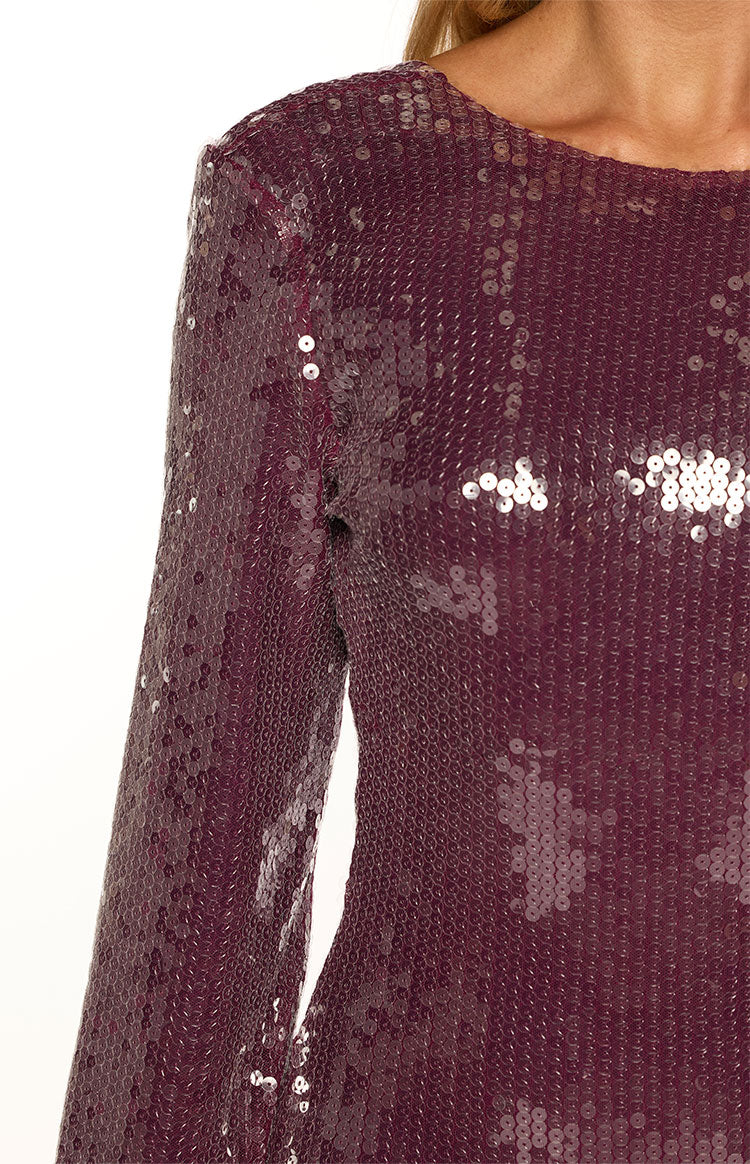 Close-up of the shimmering purple sequin fabric on the boat neck and long sleeve of the mini dress