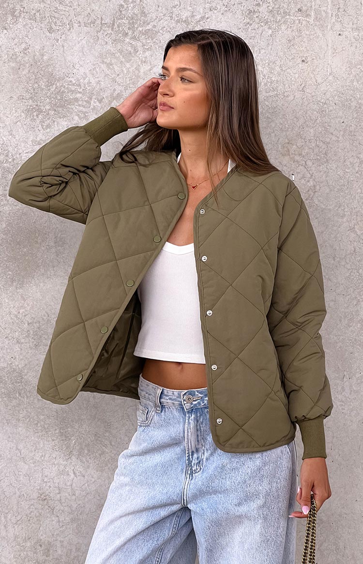 Open khaki quilted bomber jacket showing the collarless neckline, snap buttons, and ribbed cuffs