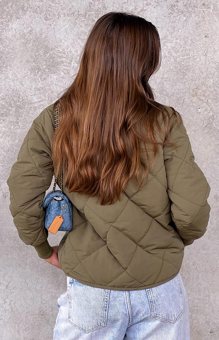 Rear view of a khaki quilted bomber jacket with diamond stitching and ribbed cuffs