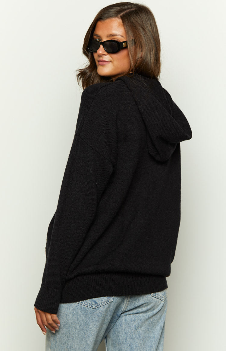 Side view of a black knitted hoodie showing the textured knit fabric, relaxed fit, and hood