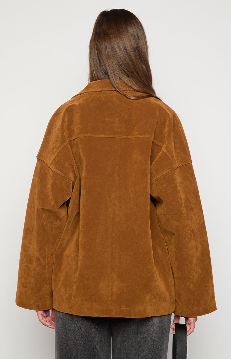 Rear view of a tan oversized suede jacket with a pointed collar, back yoke, and wide sleeves