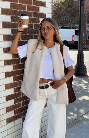 Girl in a soft cream fleece vest and white pants a trendy and cozy outfit ideal for a casual Spring day out