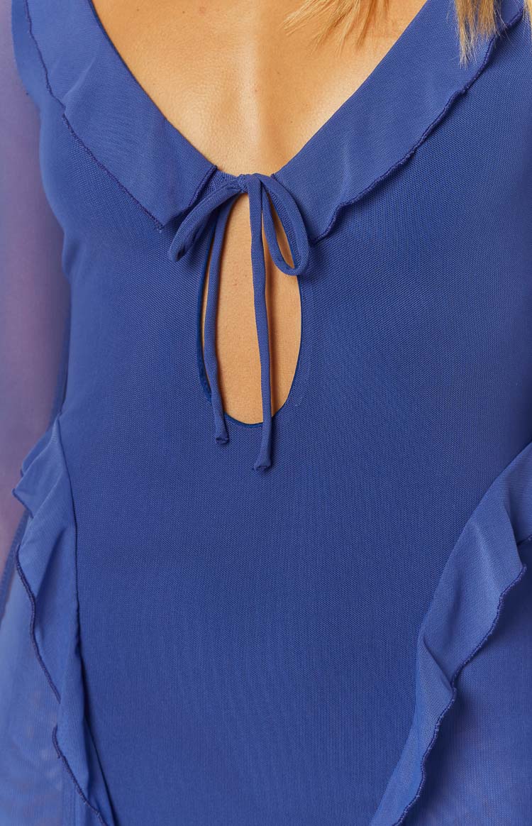 Close-up of the blue mini dress showing the V-neckline with a tie-front detail, keyhole cutout, and sheer mesh ruffled trim