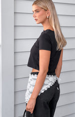 Side view of a black cropped boxy tee with short sleeves and a relaxed fit