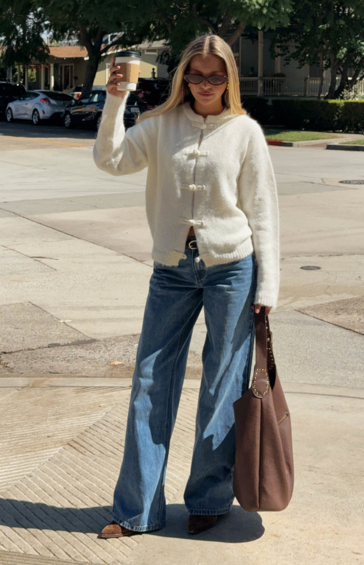 Cream fuzzy knit sweater with a round neck and three unique frog closures down the front