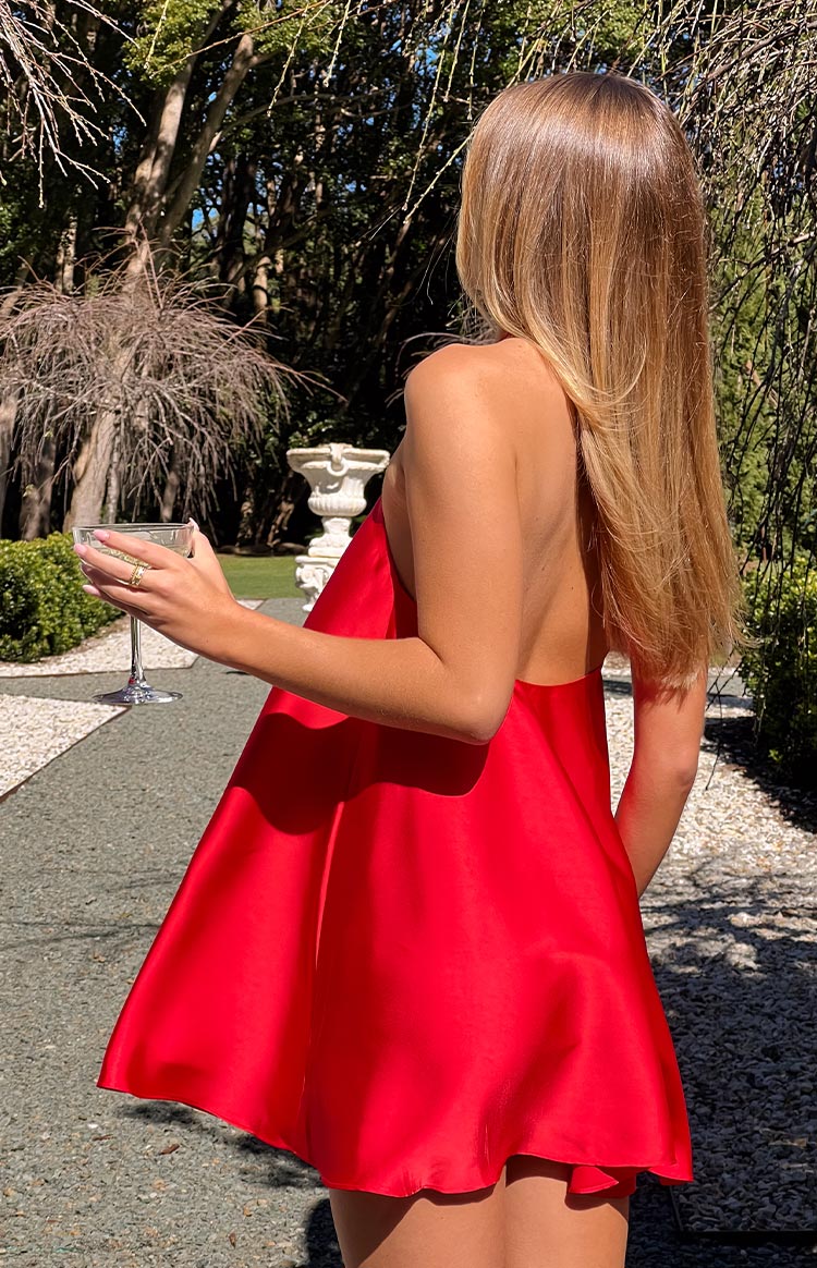 Rear and side view of a red mini dress with an open back and a flowy A-line skirt in a shiny fabric