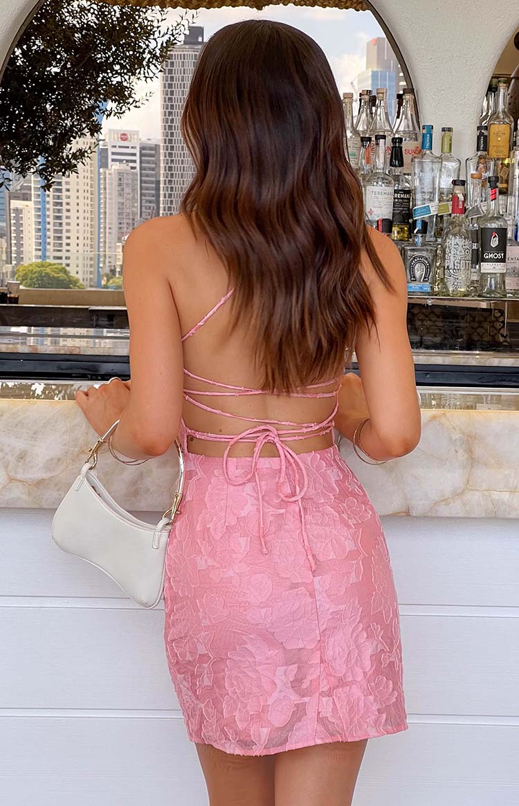 Rear view of a pink floral textured mini dress with a criss-cross strappy back and tie closure