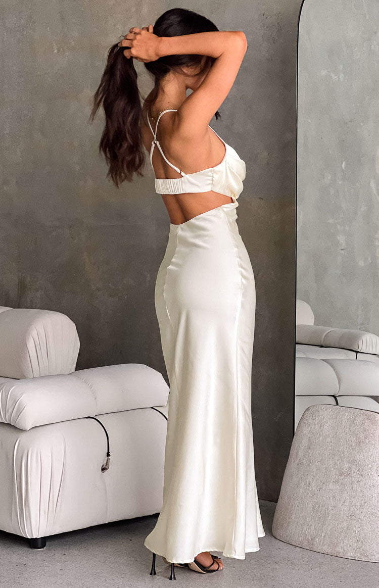 Side view of the cream satin maxi dress highlighting the open back cut-out, thin spaghetti straps, and elasticated back band