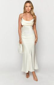 Cream satin maxi dress featuring a cowl neckline, delicate spaghetti straps, and prominent side cutouts
