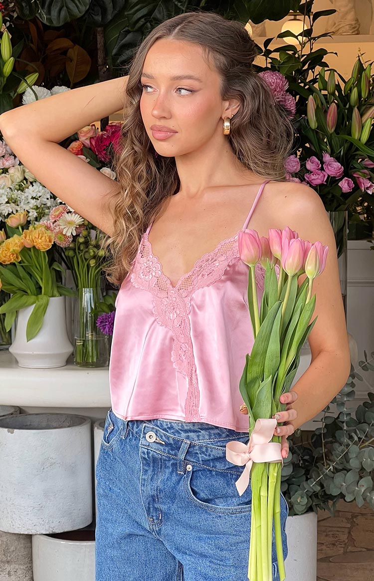 Pink satin cami top with a V-neckline and delicate lace trim along the neckline and down the front
