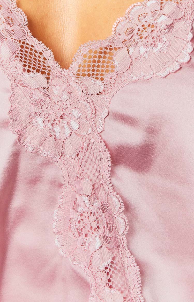 Close-up of the intricate floral pink lace trim with mesh detail along the V-neckline of a satin cami top