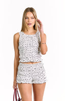 A white shorts with a black polka dot pattern, featuring tiered ruffles and an elasticated waistband. Perfectly with sleeveless crop top with tiered ruffles in a white and black polka dot print, designed to be part of a matching set.
