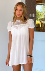 White sheer mini dress with a relaxed fit, high lace neckline, and short puff sleeves