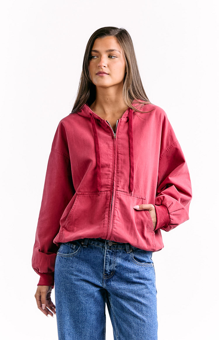 Front view of a washed red oversized hooded jacket with full zip, hood drawstrings, and large front patch pockets