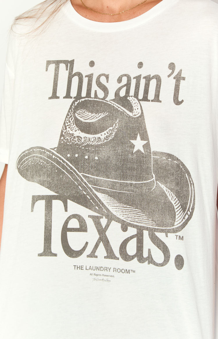 White oversized tee with a distressed grey graphic print of a cowboy hat and 'This ain't Texas' slogan