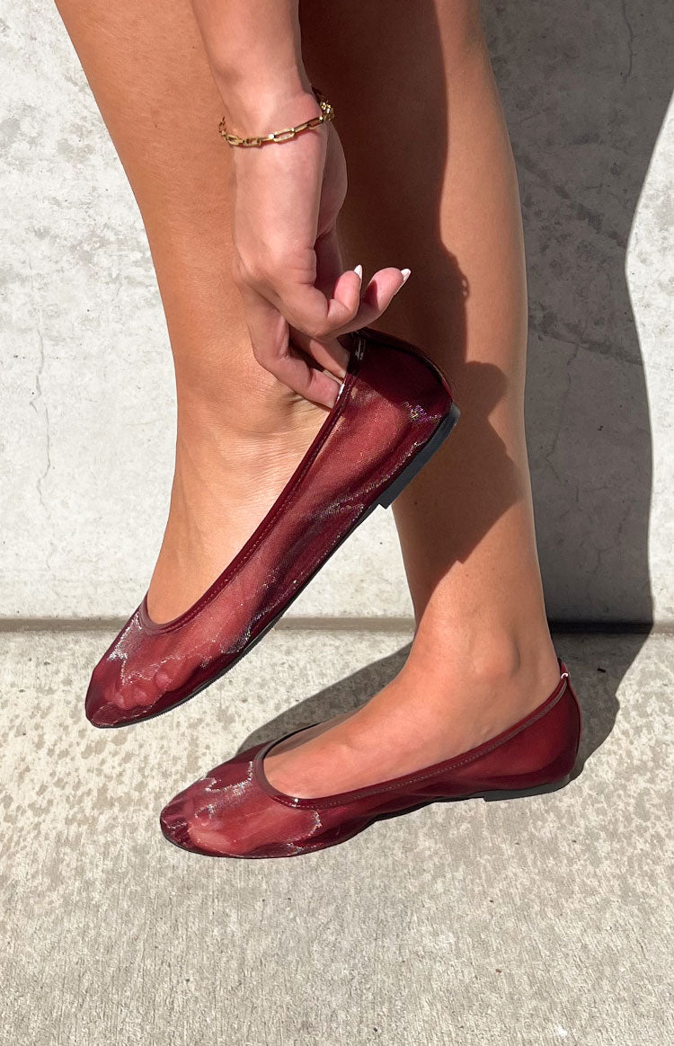 Cherry red ballet flats with a sheer mesh upper and glossy patent trim around the opening