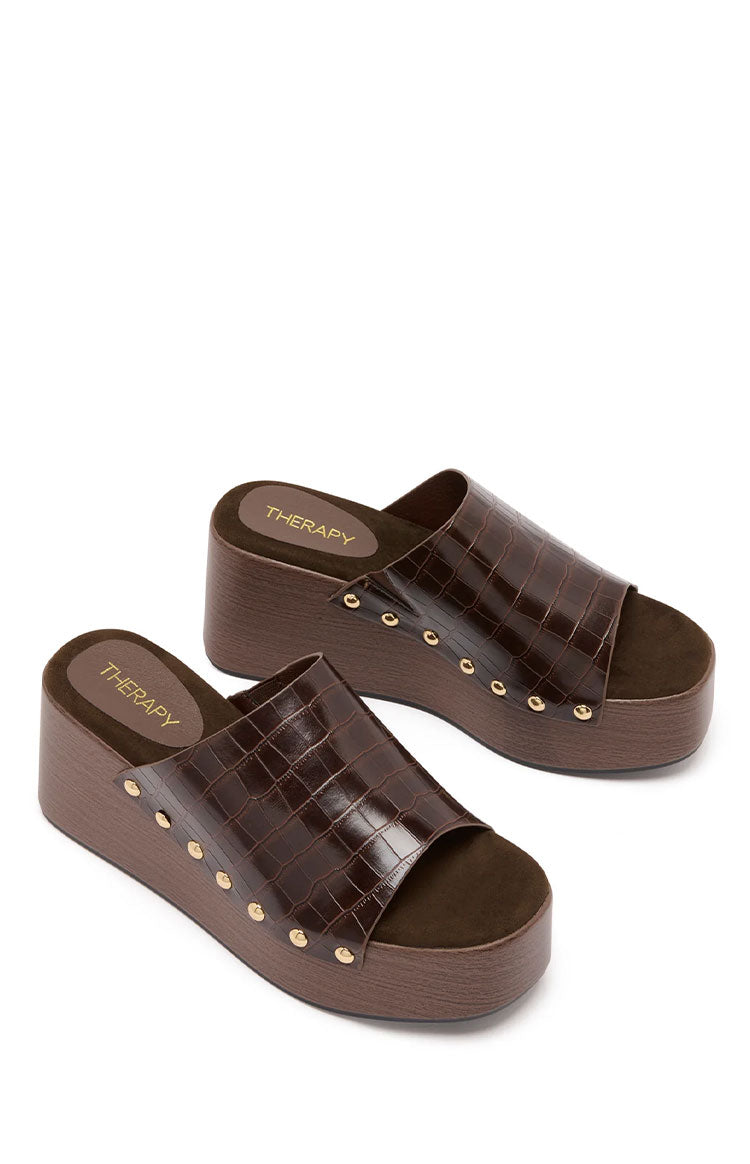 Angled view of two chocolate brown croc-embossed PU wedge sandals with gold stud details and dark brown footbeds