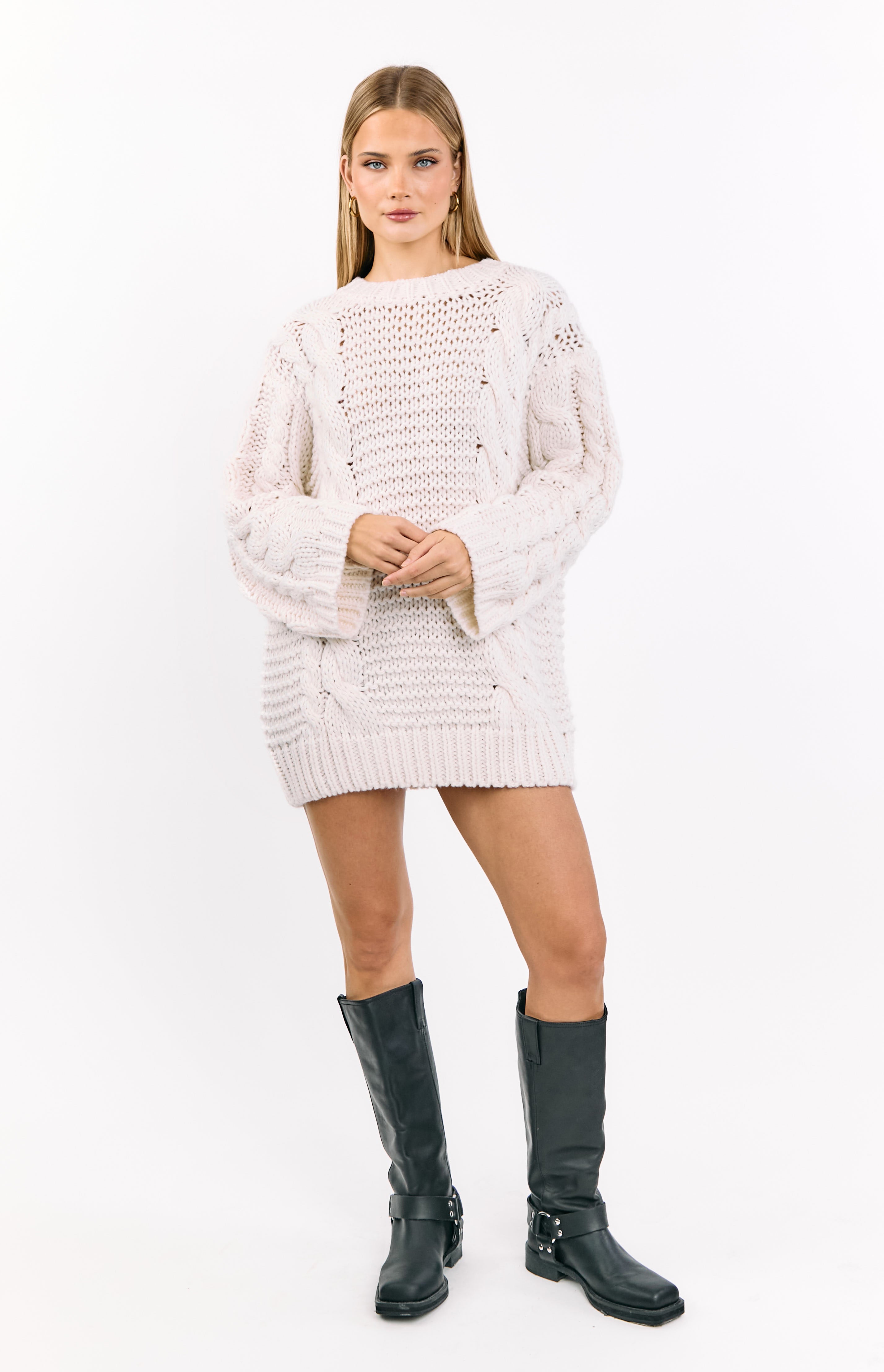 Cream cable knit sweater dress with an oversized fit, wide sleeves, and prominent open knit details