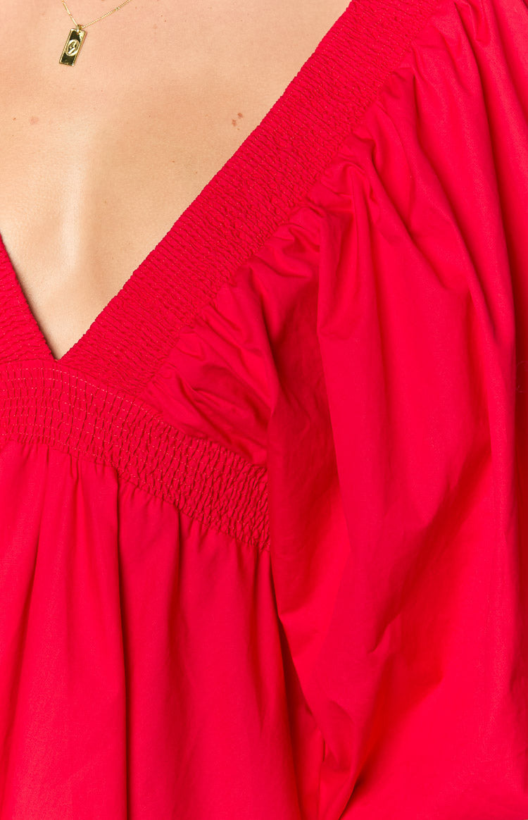 Close-up of the red mini dress showing the V-neckline, smocked bodice, and puffed short sleeve