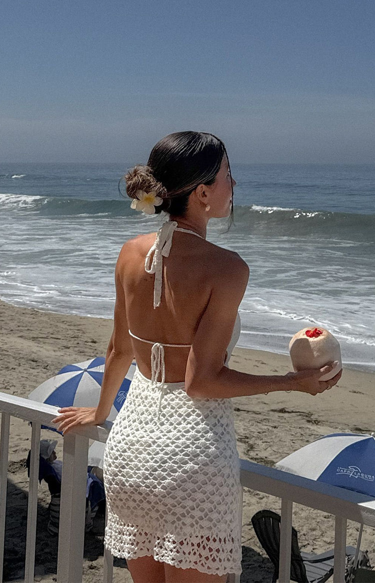 Rear view of a cream crochet mini dress showing the tied halter neck and open back with tie closure