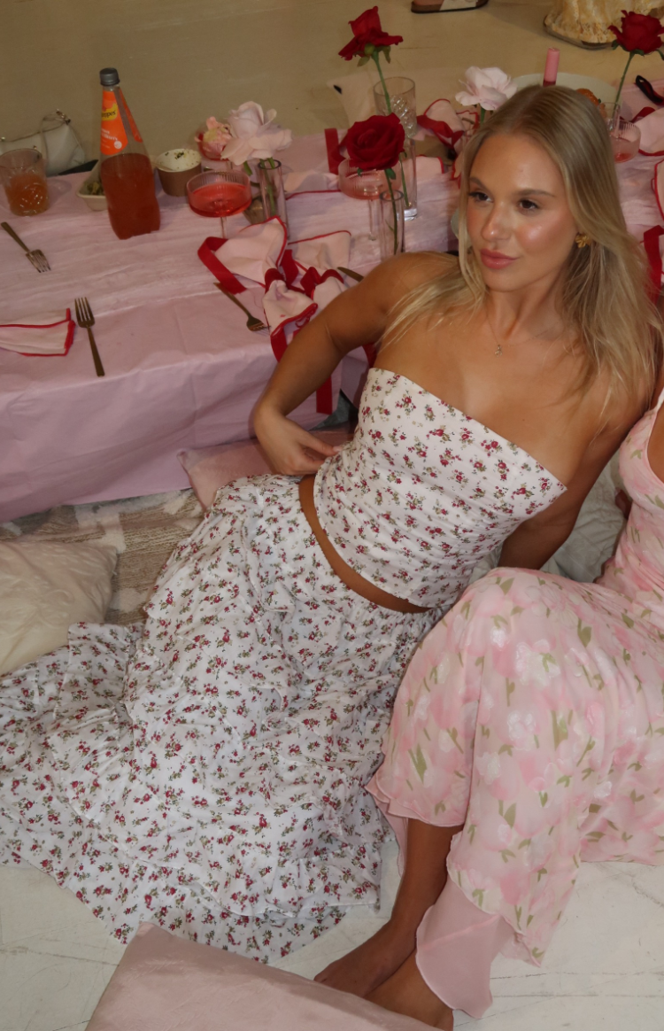 Fitted white strapless bandeau top with small red floral print, cropped at the waist